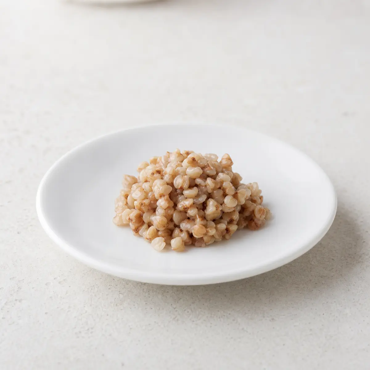 Tiny plain spoon of cooked buckwheat on a saucer