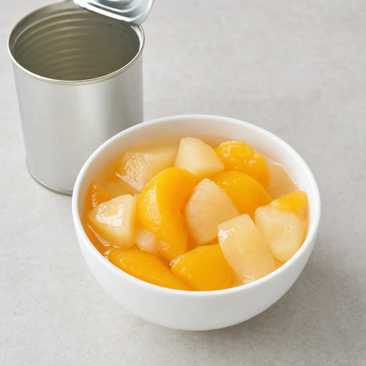 Canned peach and pear pieces in syrup in a bowl