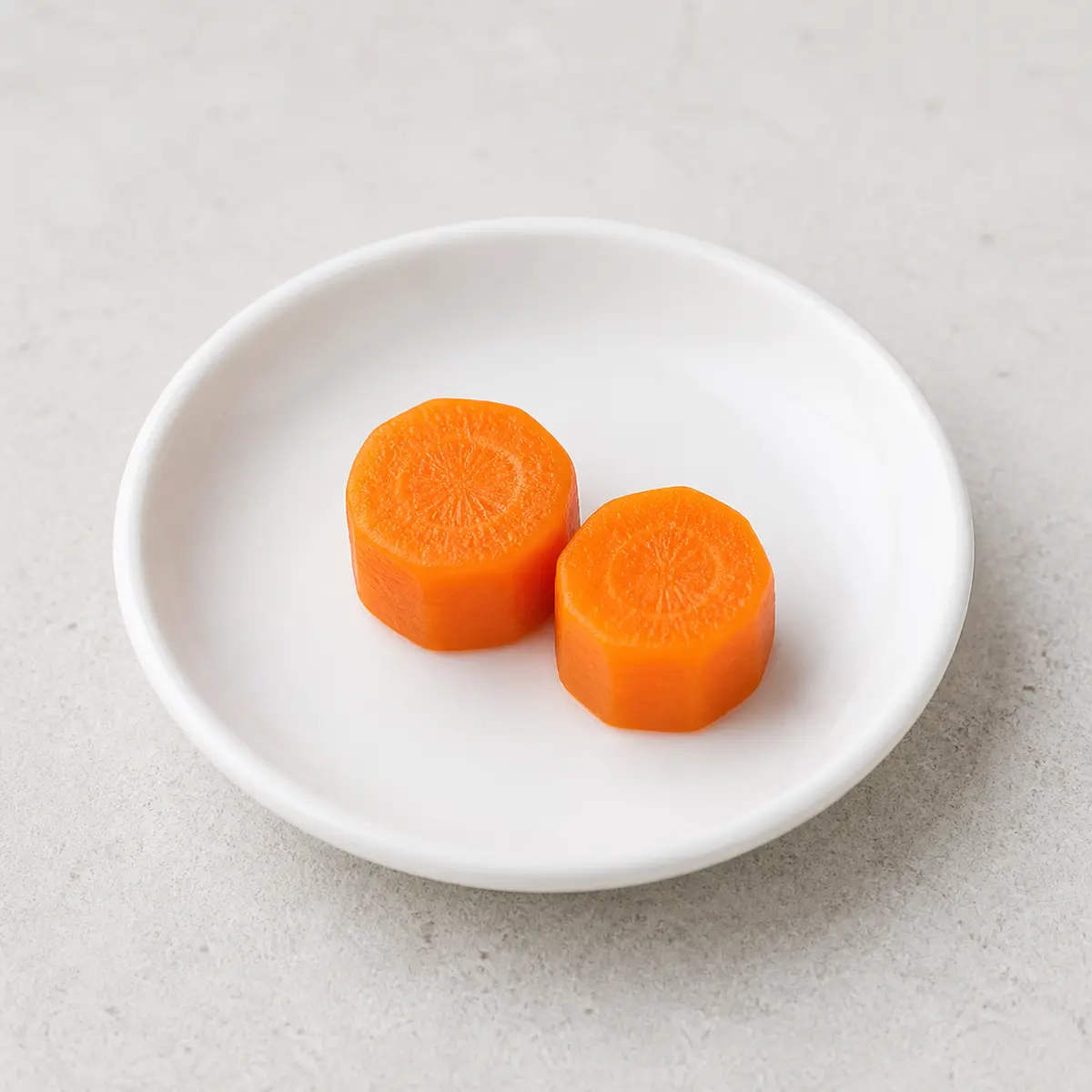 Tiny plain cooked carrot pieces on a saucer