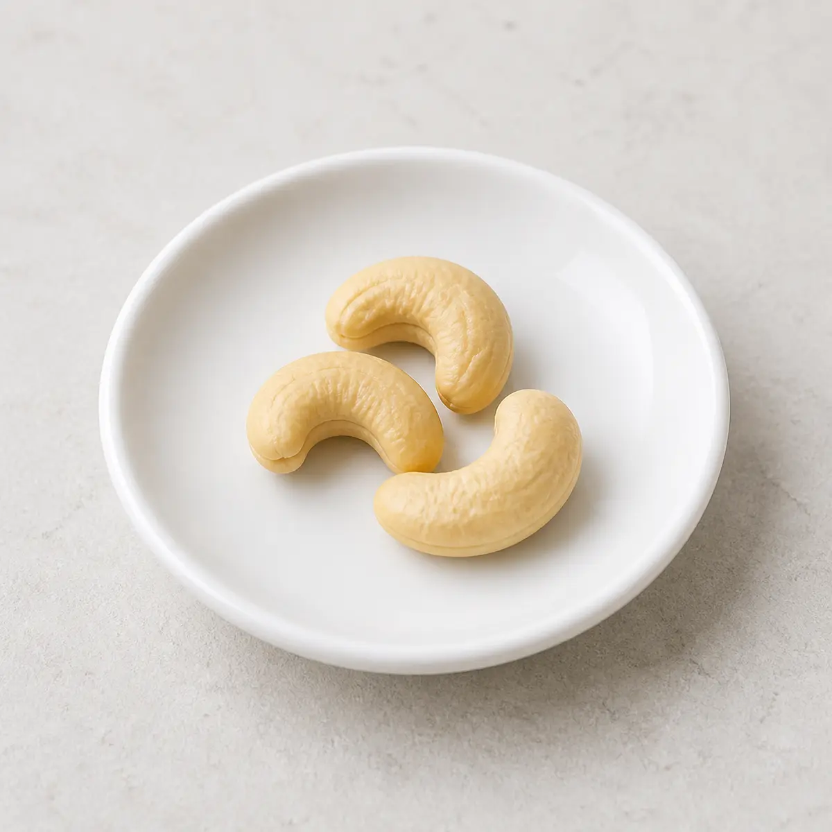 Three plain cashews on a saucer