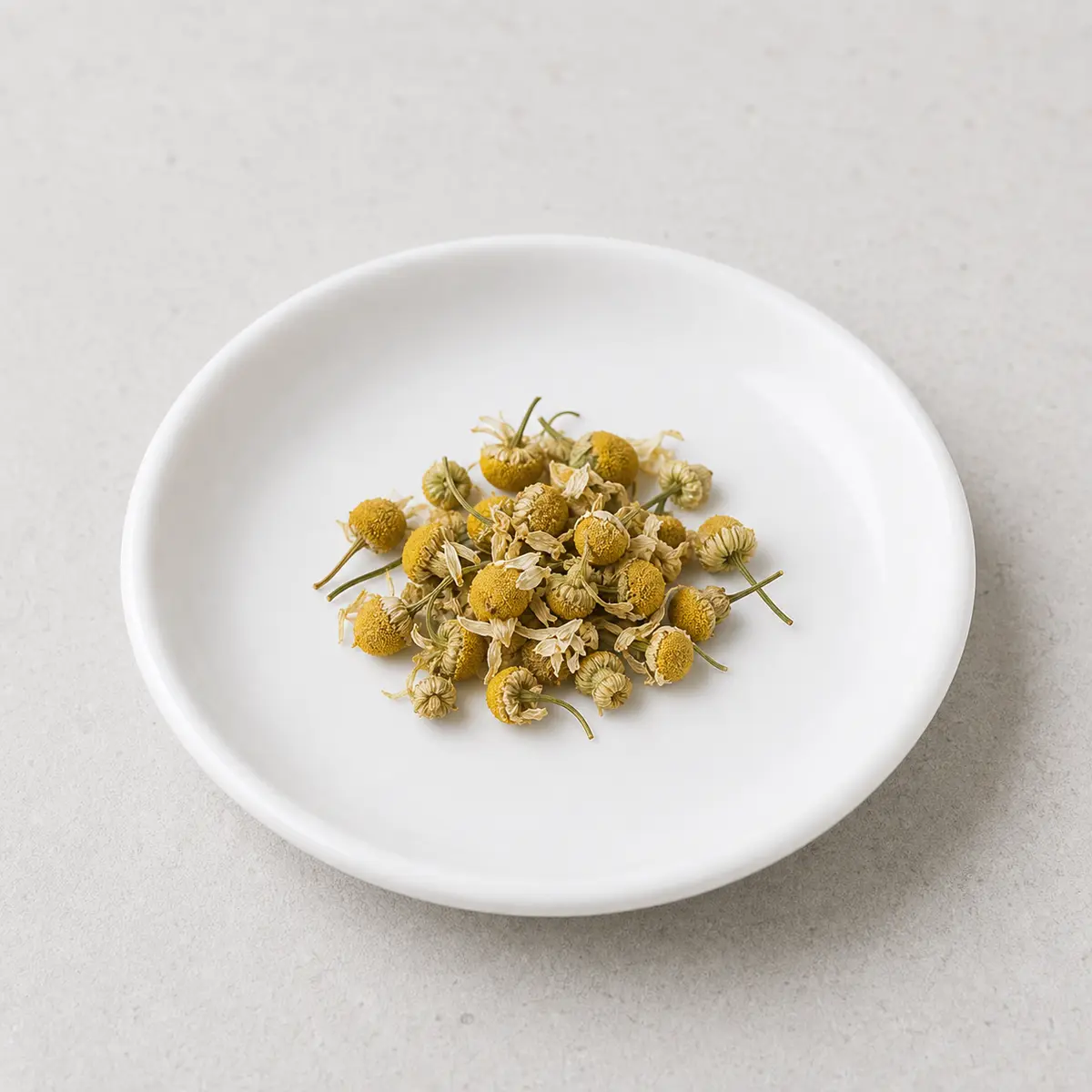 Tiny pinch of dried chamomile flowers on a saucer