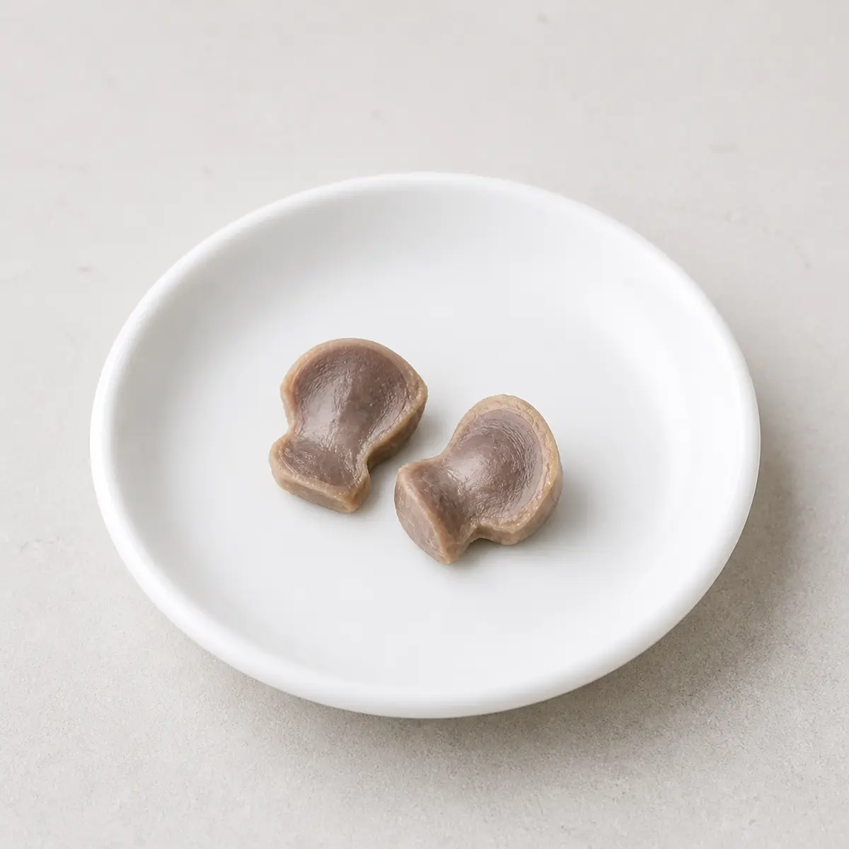 Tiny plain cooked chicken gizzard pieces on a saucer