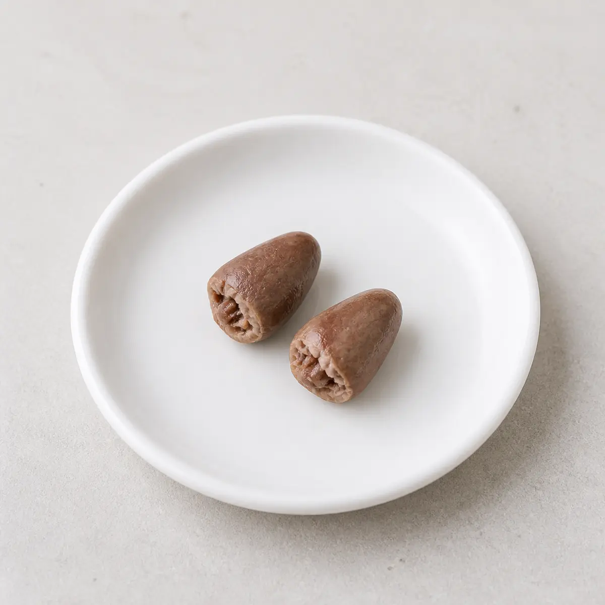 Tiny plain cooked chicken heart pieces on a saucer