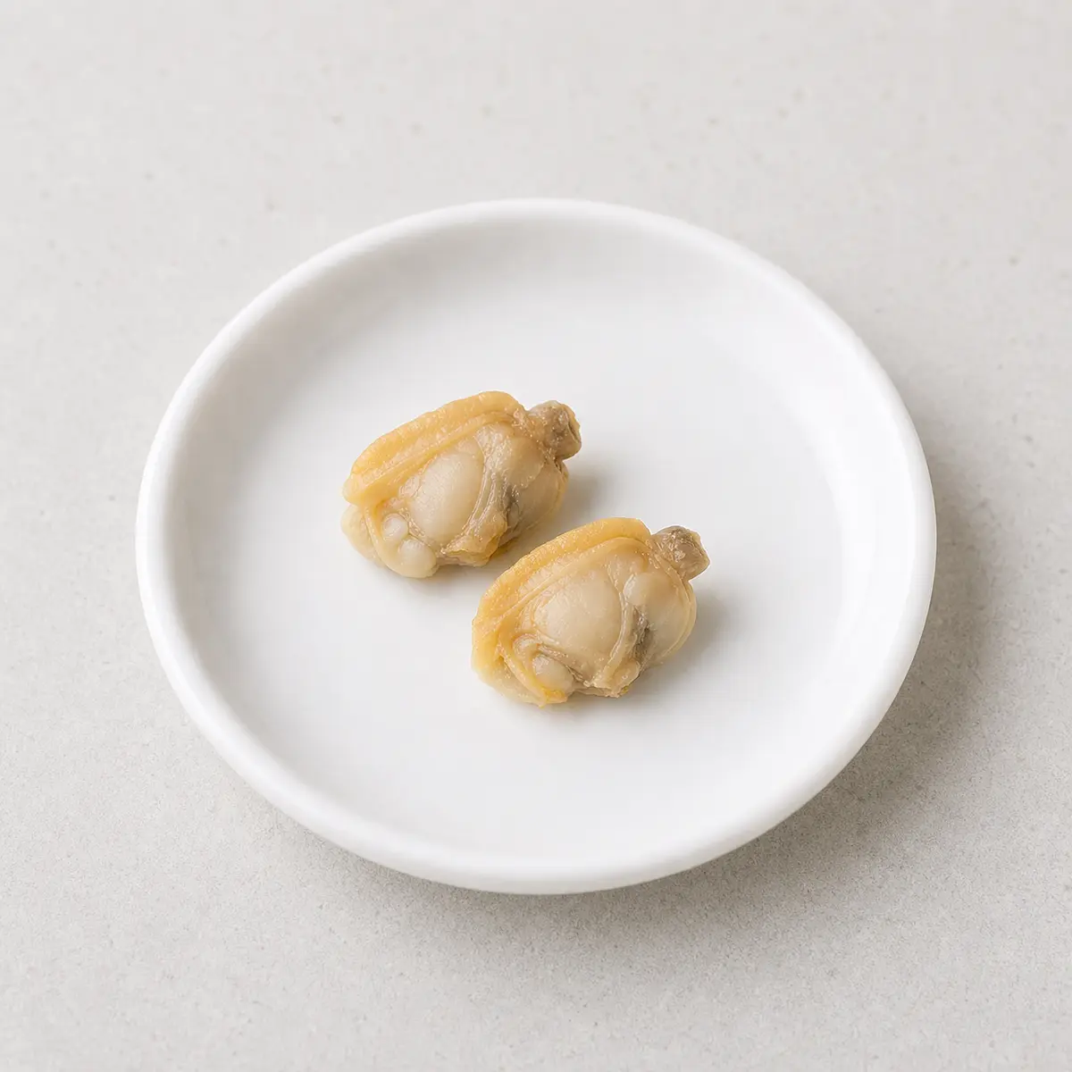 Tiny plain cooked clam pieces on a saucer