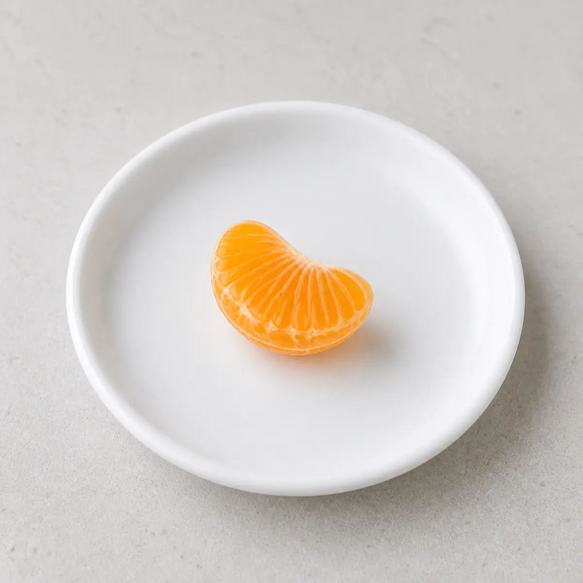 Tiny peeled clementine segment on a saucer