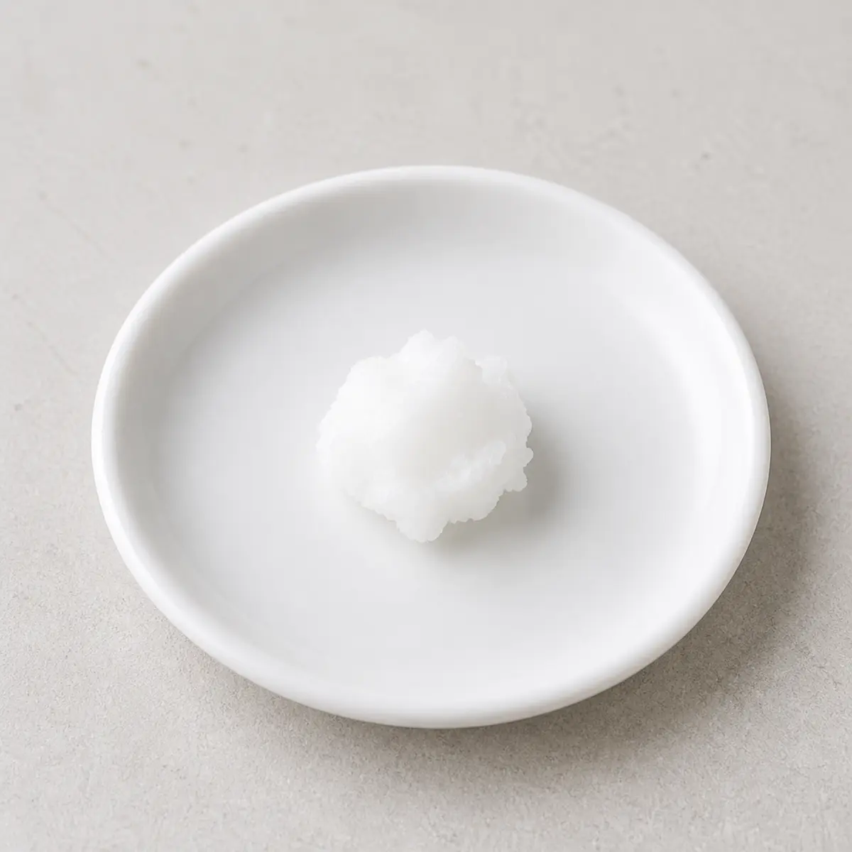 Small white coconut oil dollop on a saucer