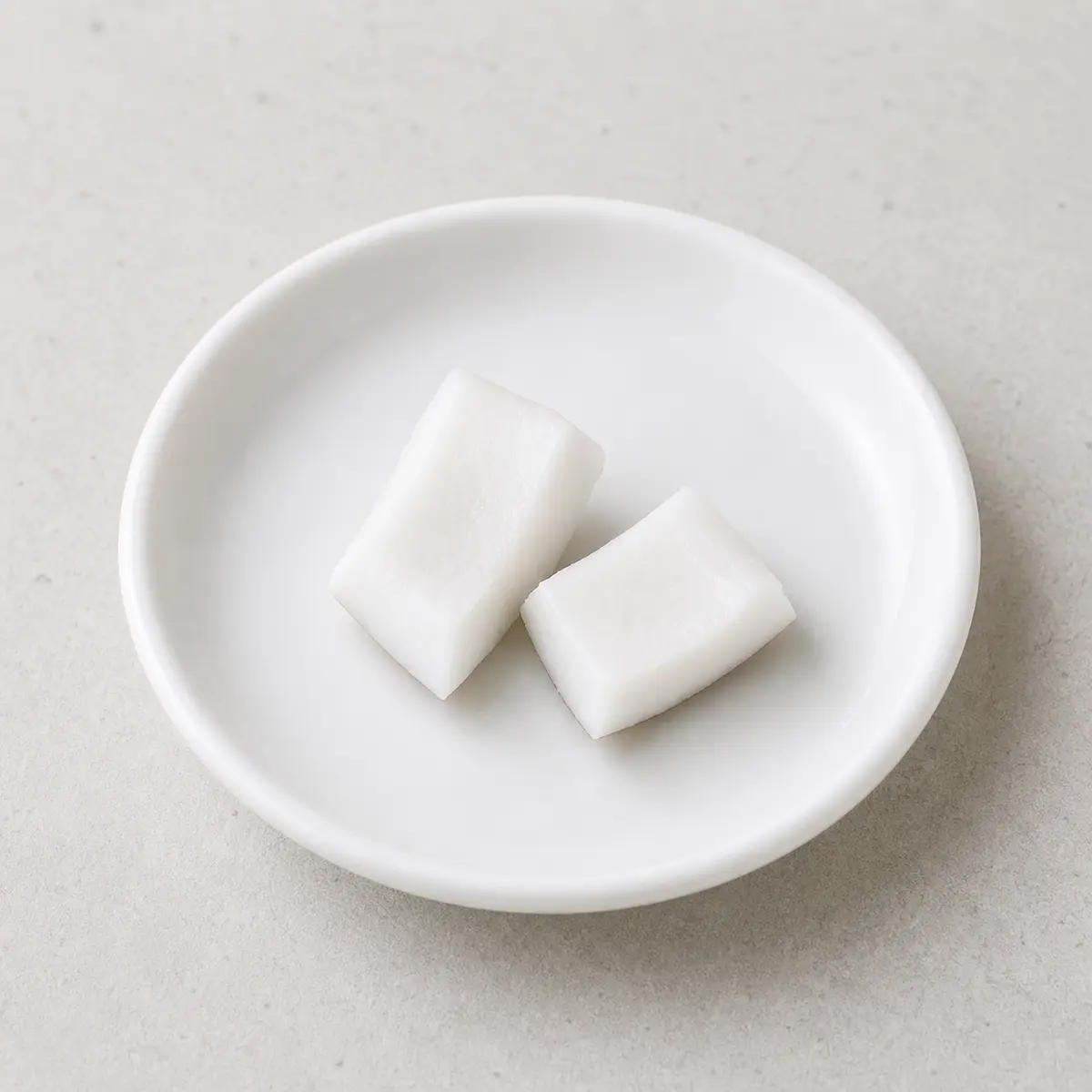 Two tiny plain coconut pieces on a saucer