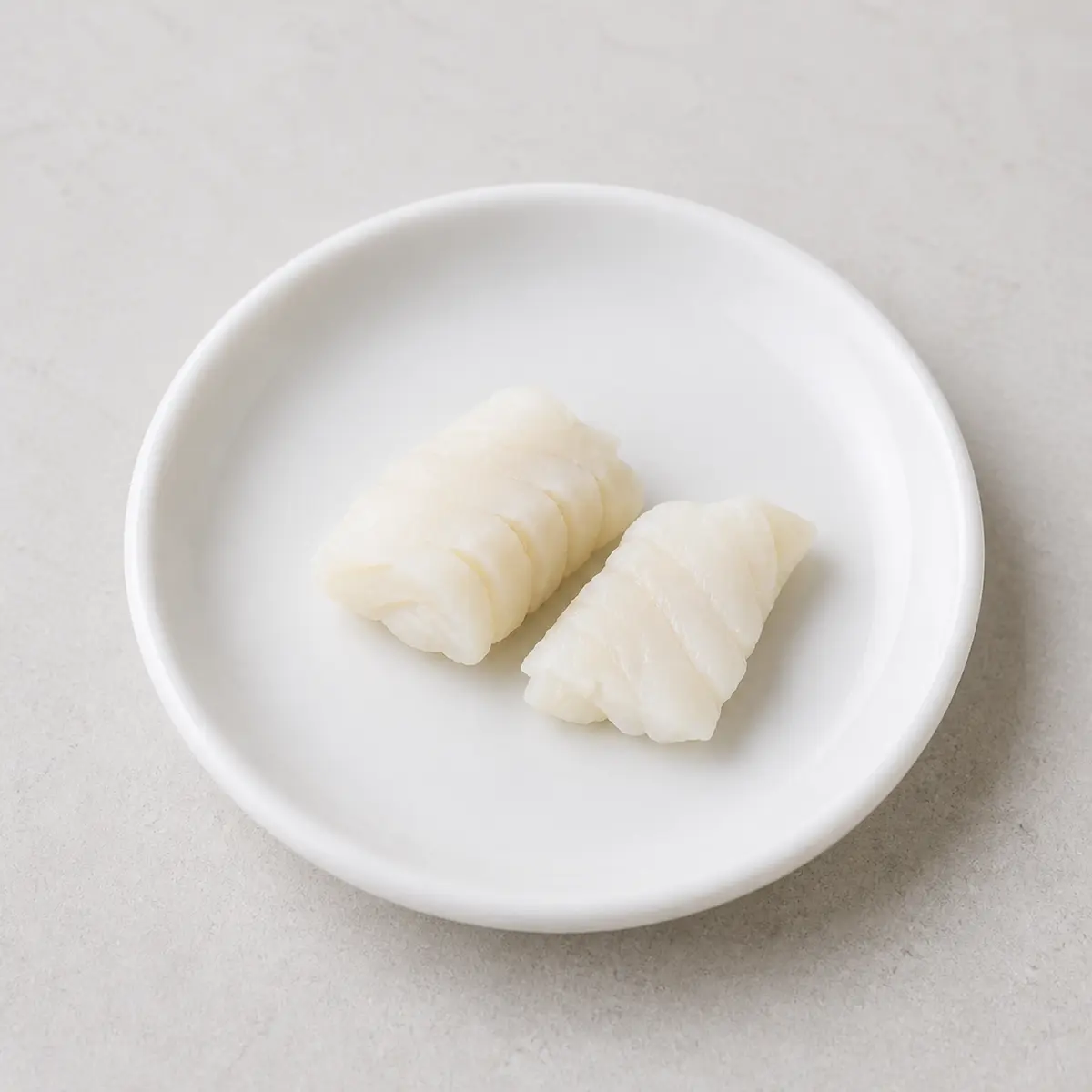 Tiny plain cooked cod flakes on a saucer
