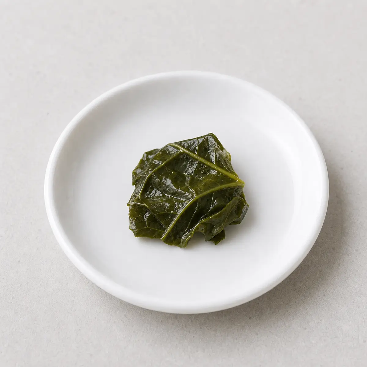 Tiny plain cooked collard greens on a saucer
