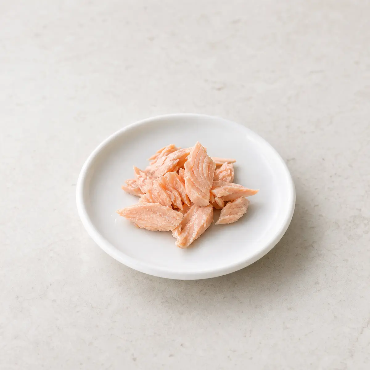 Tiny plain cooked salmon flakes on a saucer
