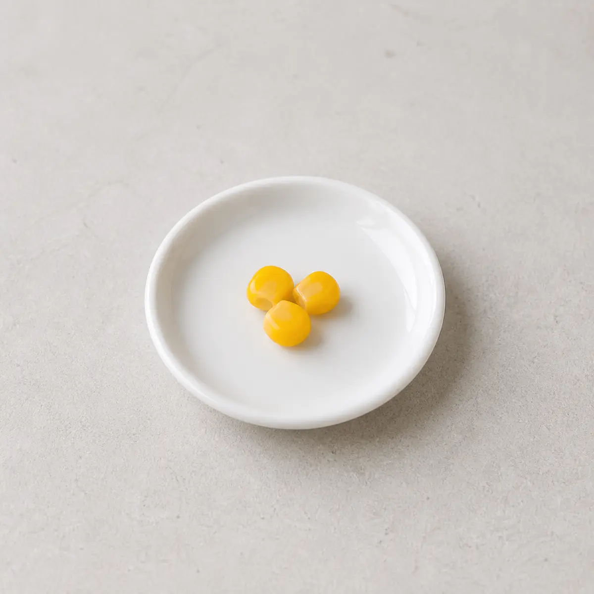 Three tiny plain cooked corn kernels on a saucer