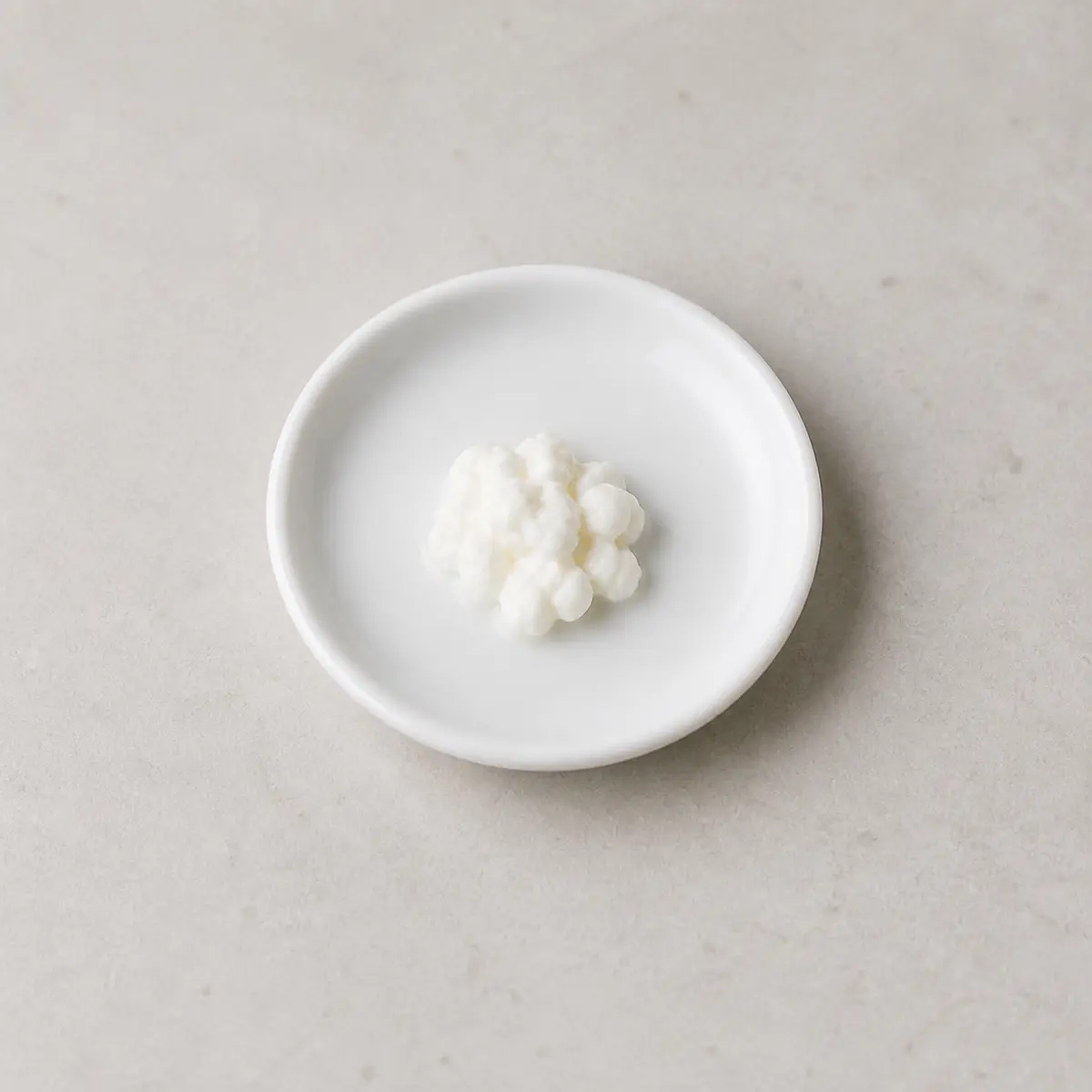 Tiny spoonful of plain cottage cheese on a saucer