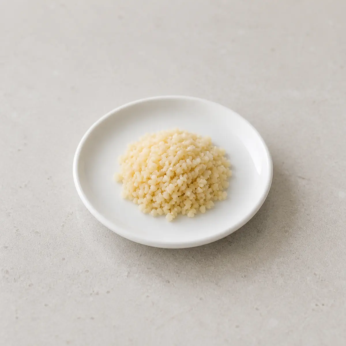 Tiny plain cooked couscous portion on a saucer