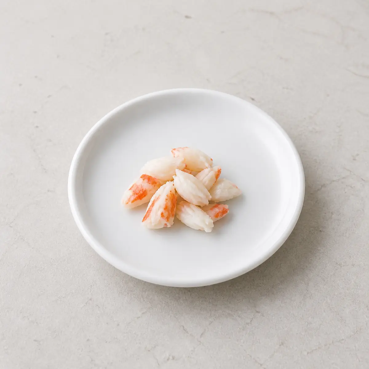Tiny plain cooked crab meat pieces on a saucer