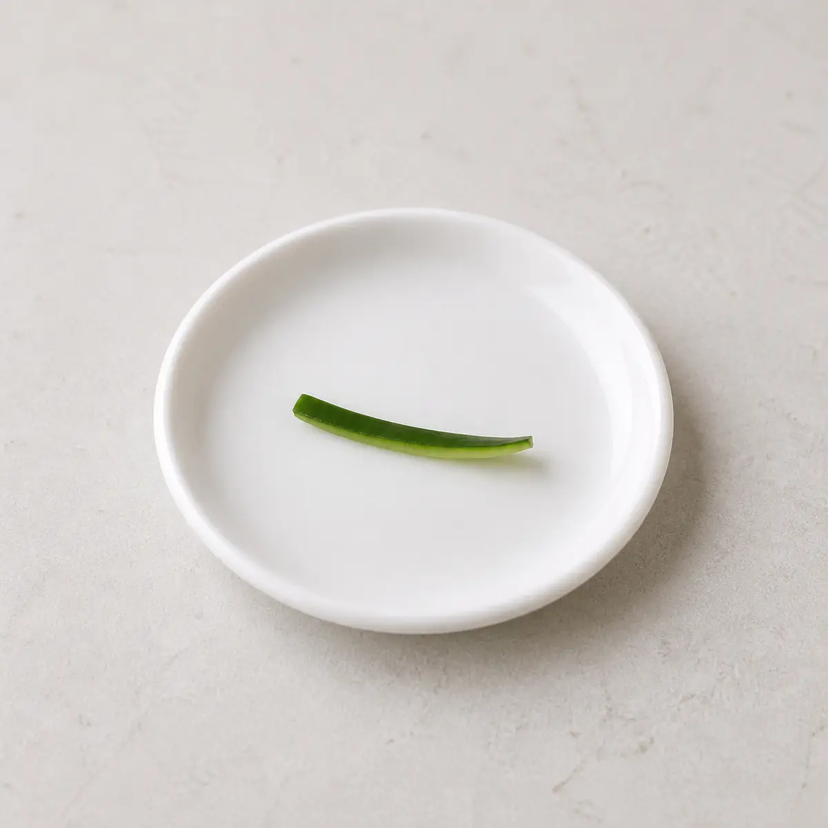 Tiny washed cucumber peel strip on a saucer