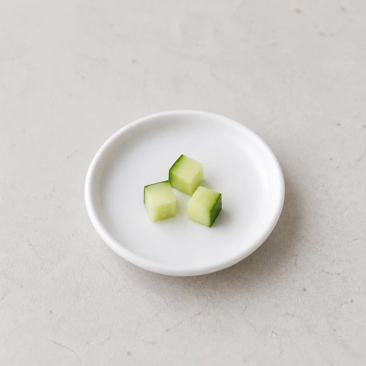Tiny plain cucumber cubes on a saucer