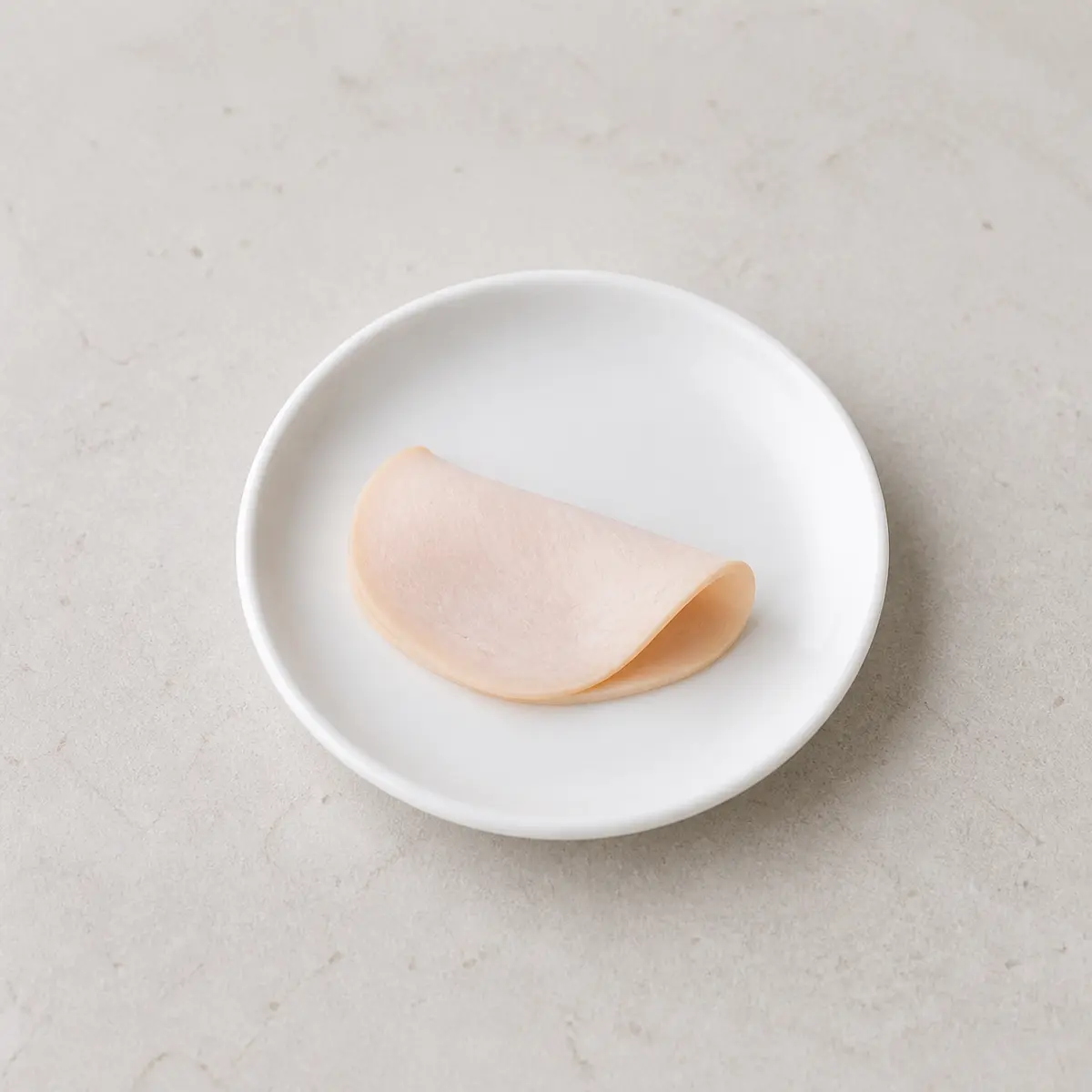 Plain deli meat slice on a white plate