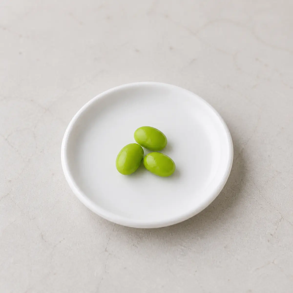 Tiny plain shelled edamame beans on a saucer