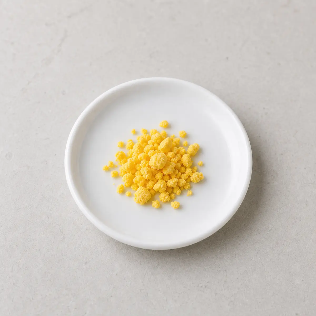 Tiny fully cooked egg yolk crumbs on a saucer