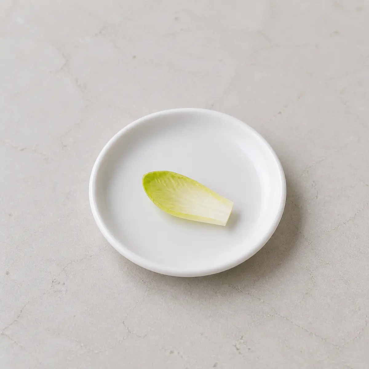 Tiny washed endive leaf piece on a saucer