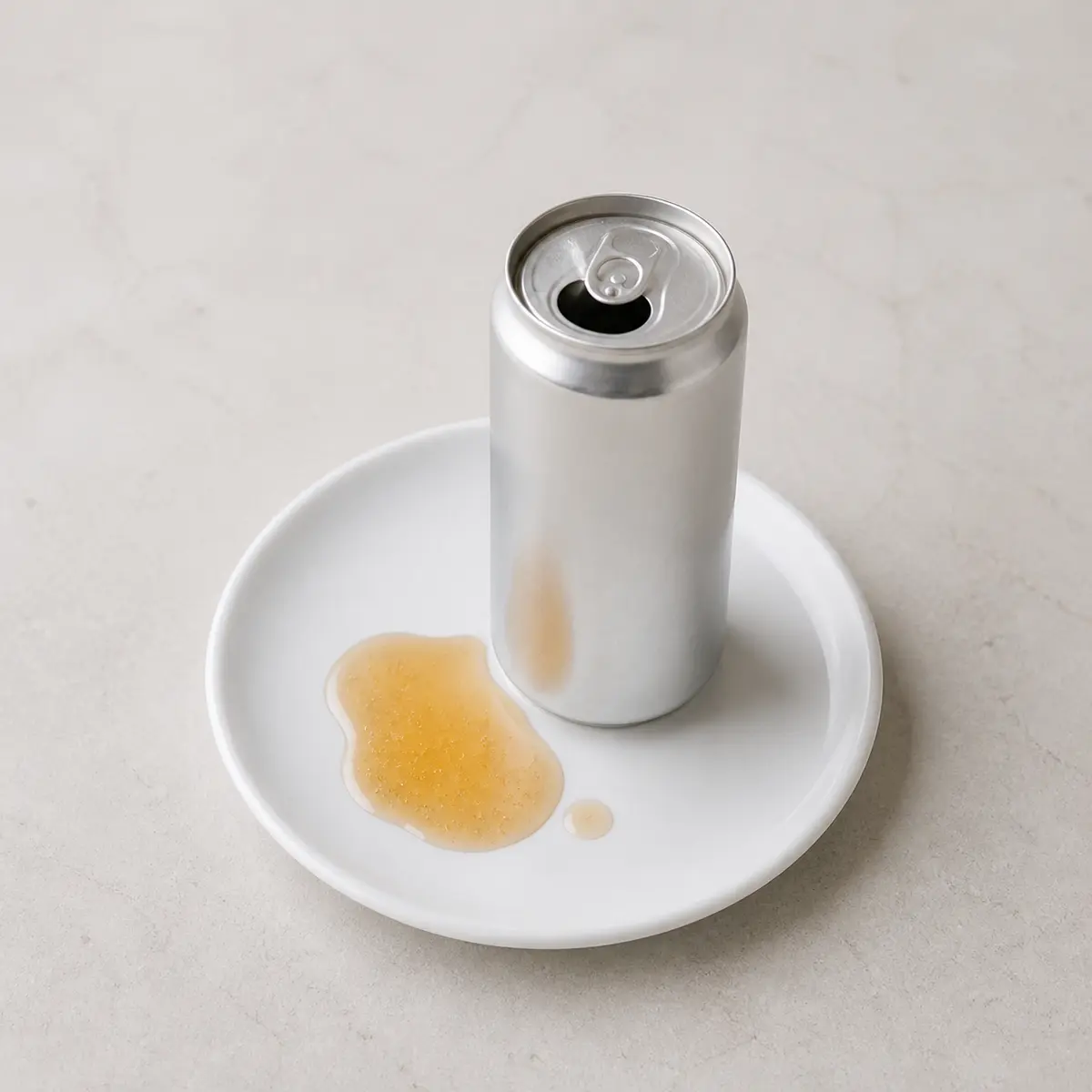 Unlabeled energy drink can with a small spill on a plate