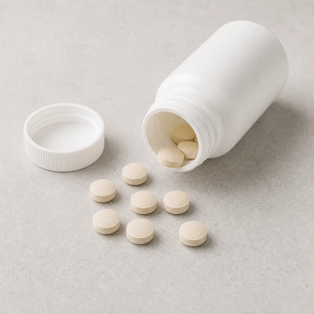 Unbranded tablets beside a blank pill bottle
