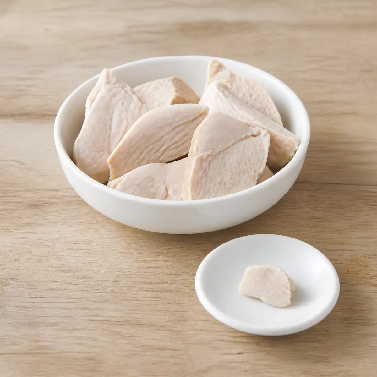 Plain cooked rabbit meat pieces with one tiny bite on a saucer