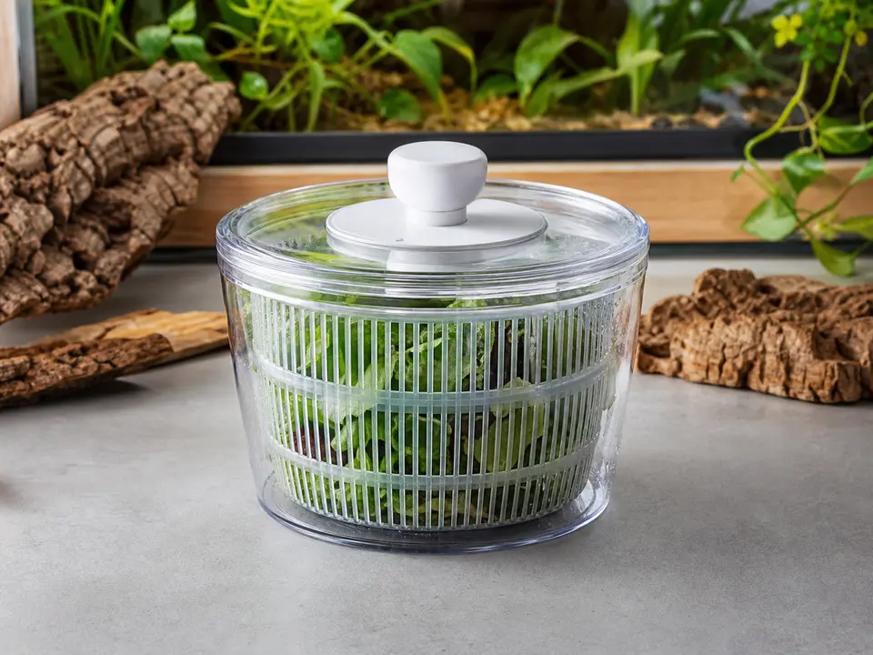 Compact clear salad spinner filled with washed leafy greens.