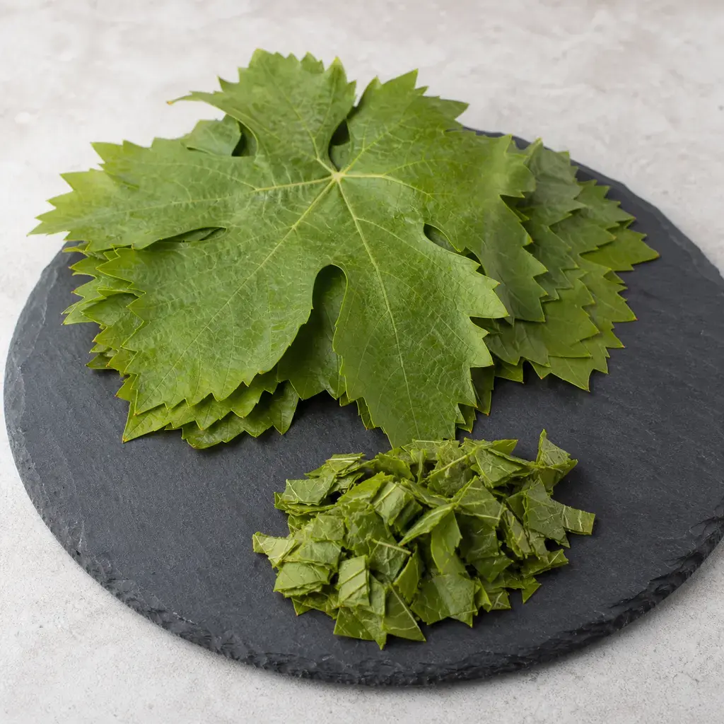 Plain grape leaves on a clean unbranded surface for a reptile food-safety check.