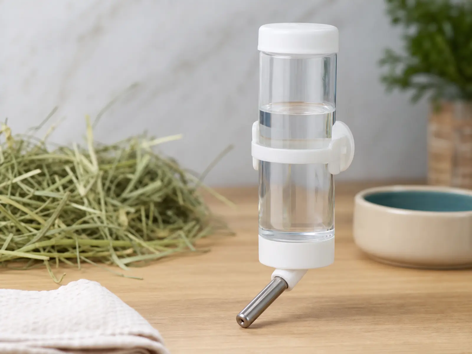 Clear small animal water bottle beside a food prep setup