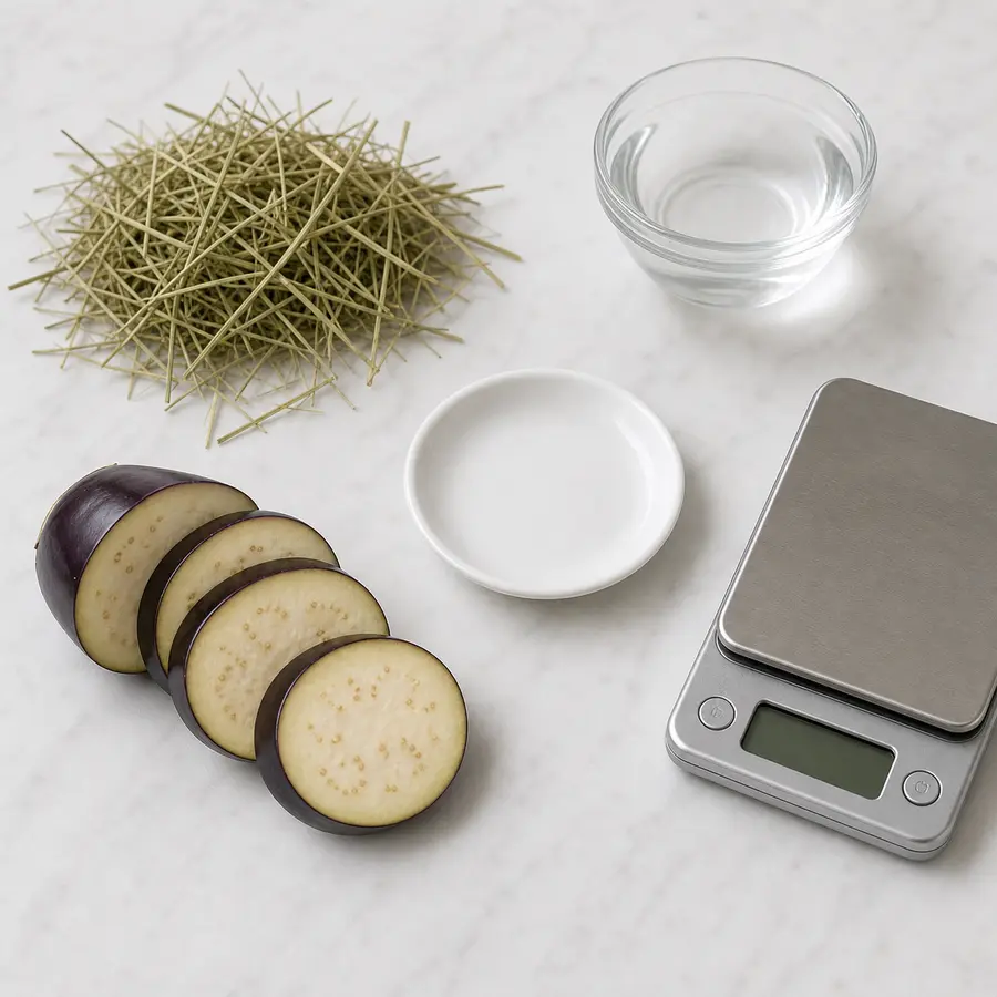 Sliced eggplant kept away from an empty saucer, hay, water, and a gram scale.